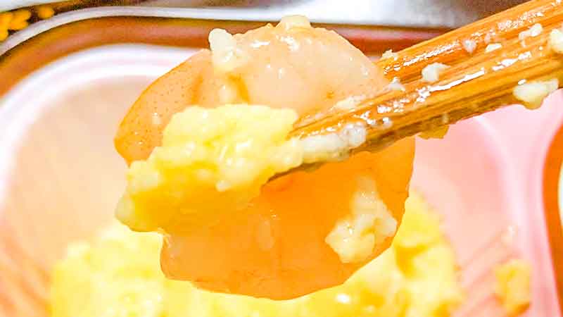 低糖質セレクトF鯵の柚庵焼きの副菜海老と卵と小松菜の和風炒めの海老を箸で持ち上げた写真です。