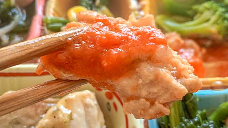 食宅便の低糖質セレクトE赤魚のソテーバター風味の副菜豚肉のトマトソースの豚肉を箸で持ち上げている写真