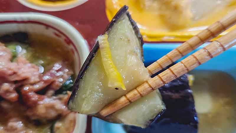 低糖質セレクトC-牛肉のXO醤炒めとツナと白菜の卵とじの副菜の揚げ茄子の煮浸しの茄子を箸で持ち上げたときの写真です。